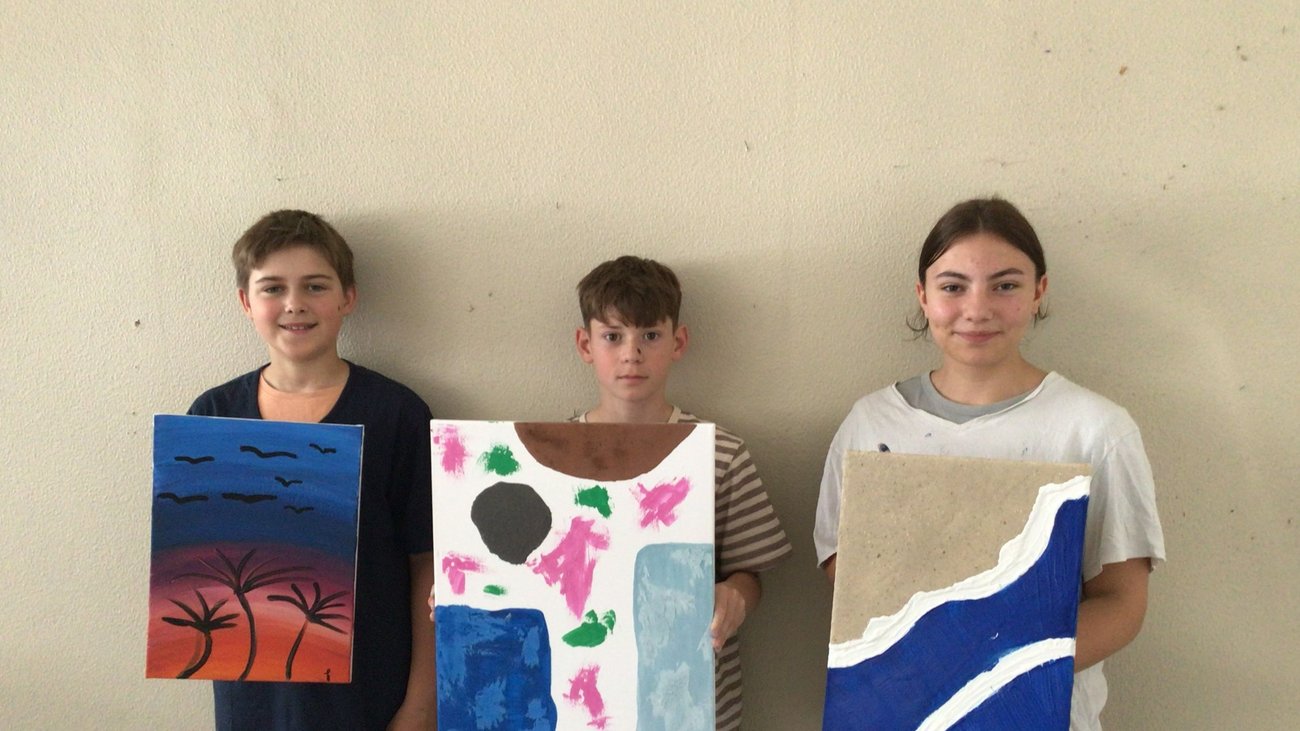 Schüler mit selbst gemalten Bildern