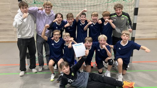 Handball-Mannschaft zeigt vor dem Tor die Siegerurkunde