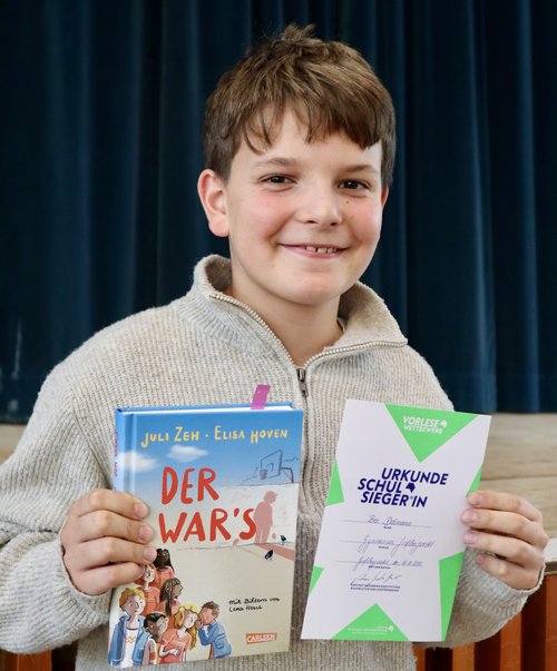 der Sieger des Vorlese-Wettbewerbs zeigt sein Buch und die Urkunde.